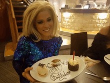 a woman in a blue sequined dress is holding a plate of food that says " happy birthday " on it