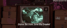 a tv screen shows a man and woman and says " damn the man. save the empire "