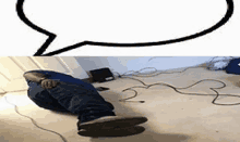 a man is laying on the floor next to a speech bubble and a cord .