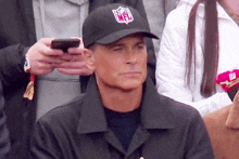 a man wearing an nfl hat is sitting in a crowd of people