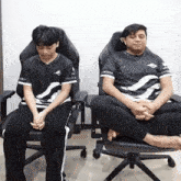 a man and a boy are sitting in chairs with their legs crossed and their shirts say team spirit