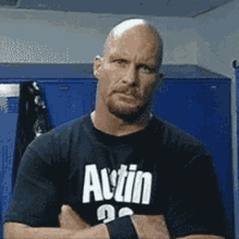 a bald man wearing a black shirt with the word austin on it is standing in a locker room .