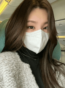 a woman wearing a face mask is sitting on a plane