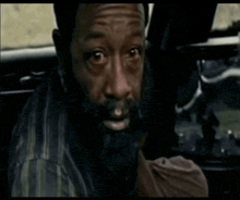 a man with a beard is sitting in a car looking at the camera