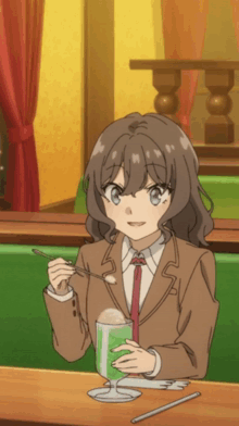 a girl is sitting at a table with a spoon in her mouth