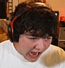 a man wearing headphones is making a funny face while playing a video game .