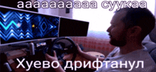 a man holding a steering wheel in front of a computer screen that says " aa "