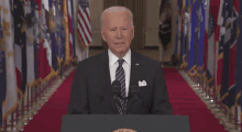 a man in a suit and tie is standing in front of a podium with the words and it must stop written below him .