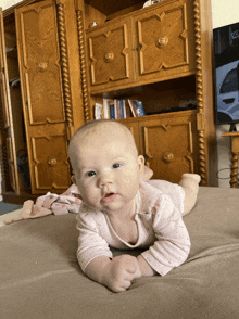 a baby laying on its stomach in front of a wooden dresser