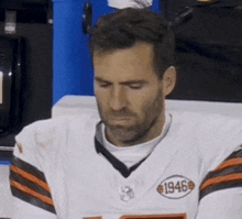 a man wearing a 1946 jersey sits on a bench with his eyes closed