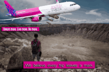 a wizz airplane is flying over a desert with a man standing in front of it