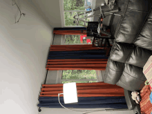 a living room with a black leather couch and orange curtains