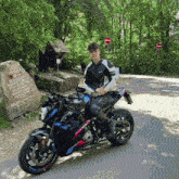 a young man is sitting on a motorcycle in front of a large rock that says ' stefan schulze ' on it