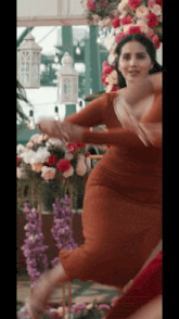 a woman in a dress is dancing in front of flowers