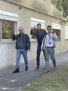 three men standing in front of a building with shutters