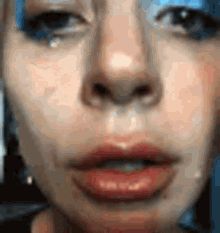 a close up of a woman 's face with blue eye shadow on .