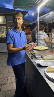 a man in a blue shirt is standing in front of a counter with a woman in a striped shirt behind him