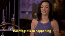 a woman in a blue tank top is saying hashtag it 's all happening