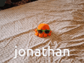a stuffed octopus wearing sunglasses is on a bed with the name jonathan