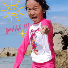 a young girl wearing a pink shirt with mickey mouse on it