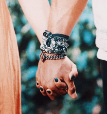 a man and a woman holding hands with bracelets on