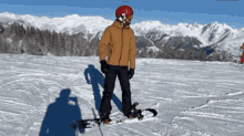 a man wearing a helmet and goggles is standing on a snowboard on top of a snow covered slope .