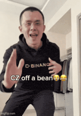 a man wearing a binance hoodie is dancing in a room