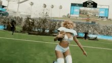 a woman in a bra and shorts is running on a football field .