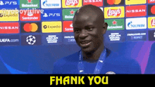 a man with a medal around his neck is standing in front of a banner that says " thank you "