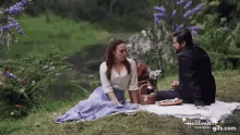 a man and a woman are having a picnic in a park .