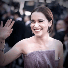 a woman in a purple dress smiles and waves