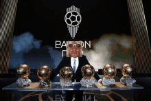 a man in a suit stands in front of a sign that says " baron "