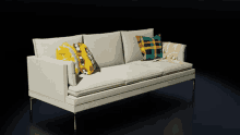 a white couch with pillows and a blanket on it against a black background