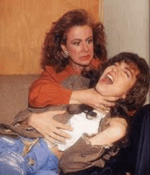 a woman is holding another woman 's neck while laughing .