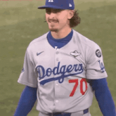 a man wearing a dodgers jersey and a blue hat is standing on a field .