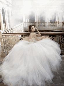 a woman in a ball gown is sitting on a balcony