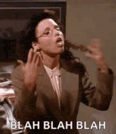 a woman in a suit and glasses is making a funny face and sticking her tongue out .