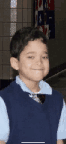 a young boy wearing a blue vest and a blue shirt