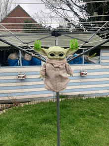 a baby yoda doll is sitting on a clothes line