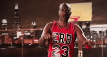 a bald man in a red basketball jersey with the number 23 on it is dancing .