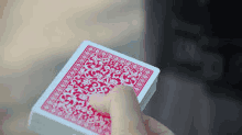 a person is holding a stack of red and white playing cards .