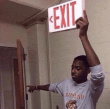 a man is holding an exit sign above his head .