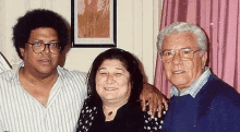 a man and two women are posing for a picture together in a room .