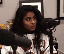 a woman is sitting in front of a microphone wearing a jersey with the number 23 on it .