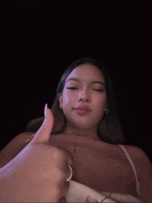 a woman giving a thumbs up with a cross necklace around her neck