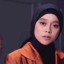 a woman wearing a hijab and an orange jacket