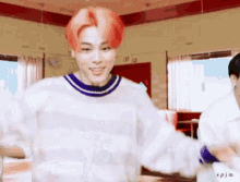 a young man with red hair is dancing in a diner while wearing a white sweater .