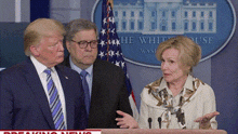 a man in a suit and tie stands next to a woman behind a podium in front of a white house sign