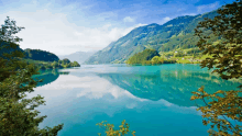 a lake surrounded by mountains and trees with a blue sky