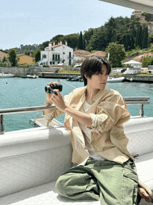 a young man sitting on a boat taking a picture